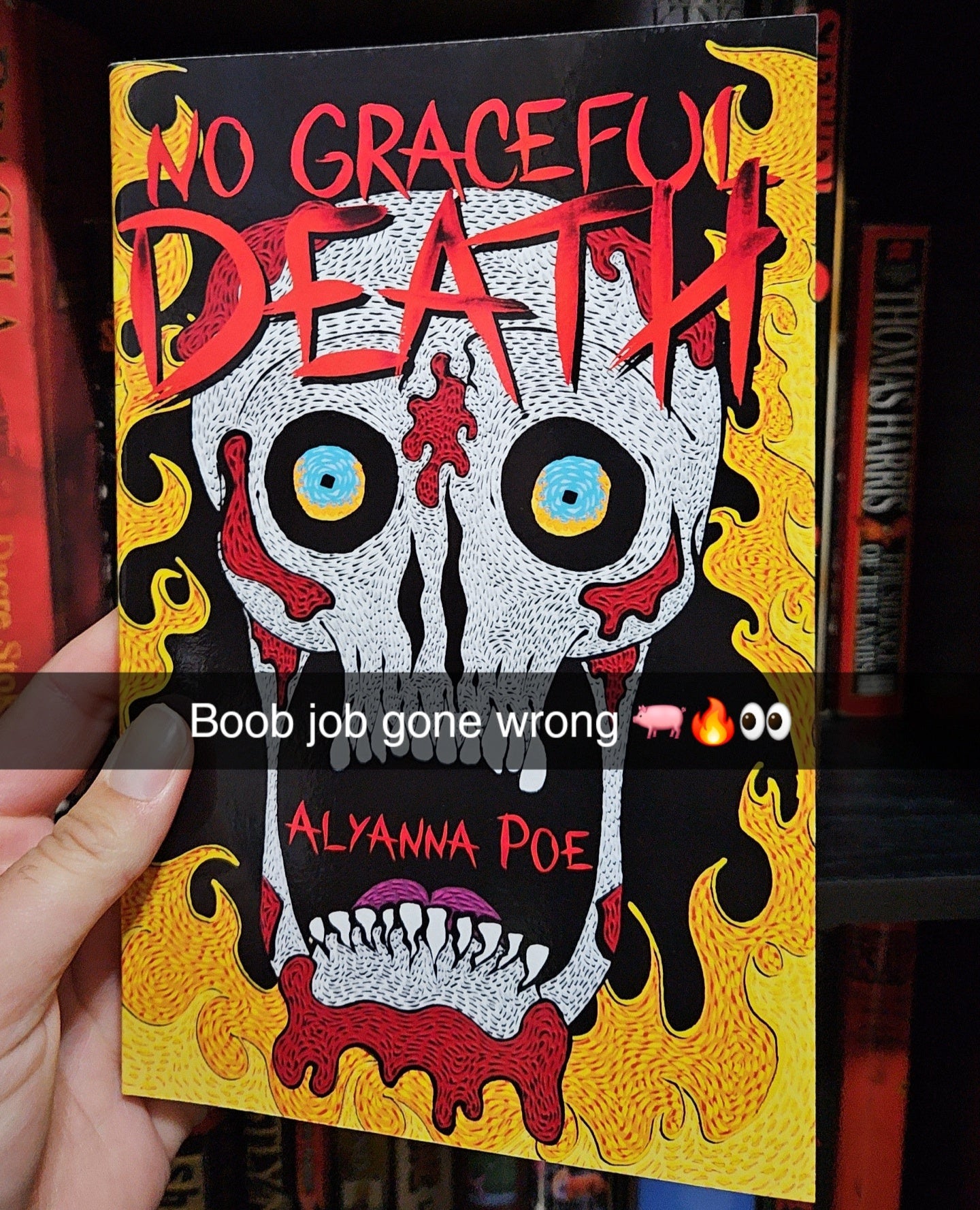 Book titled 'No Graceful Death' by Alyanna Poe held in front of a bookshelf.